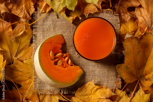 A glass of pumpkin juice with a piece of pumpkin in the foliage