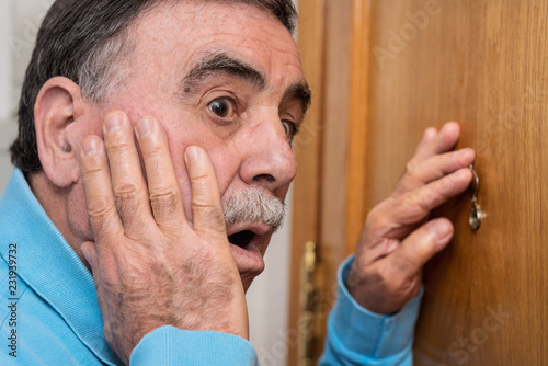 Senior man looking through peephole photo