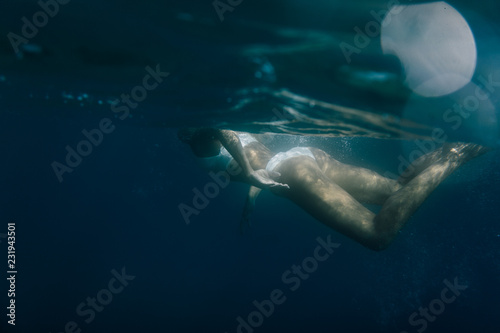 Wide shot of a woman swimming underwater photo