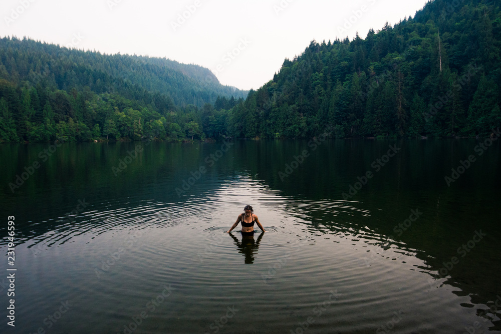 A young woman in chest deep water in a lake on a smoky evening A young woman in chest deep water in a lake on a smoky evening