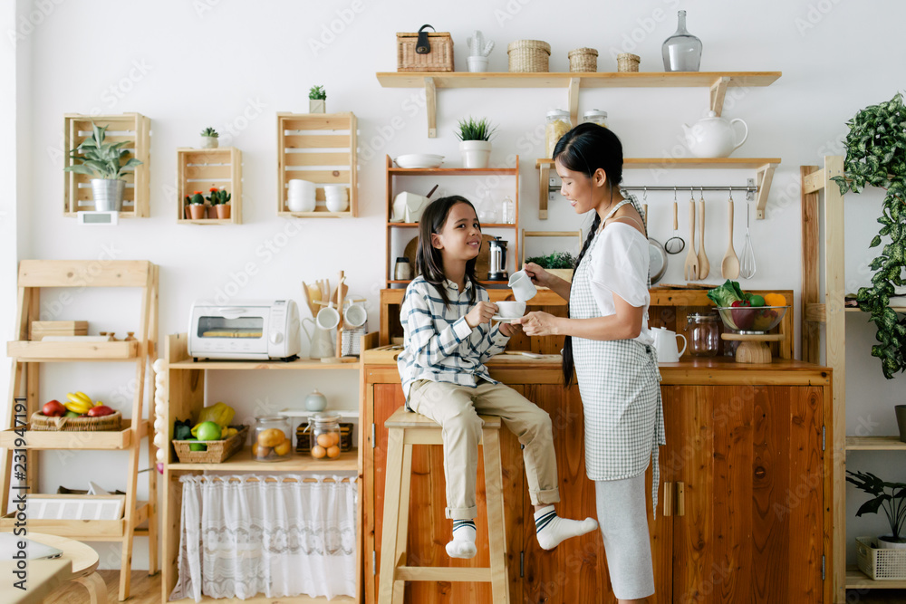 Mother and child making tea together in the wooden kitchen Mother and child making tea together in the wooden kitchen