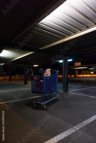 Cheerful woman lying in shopping trolley photo