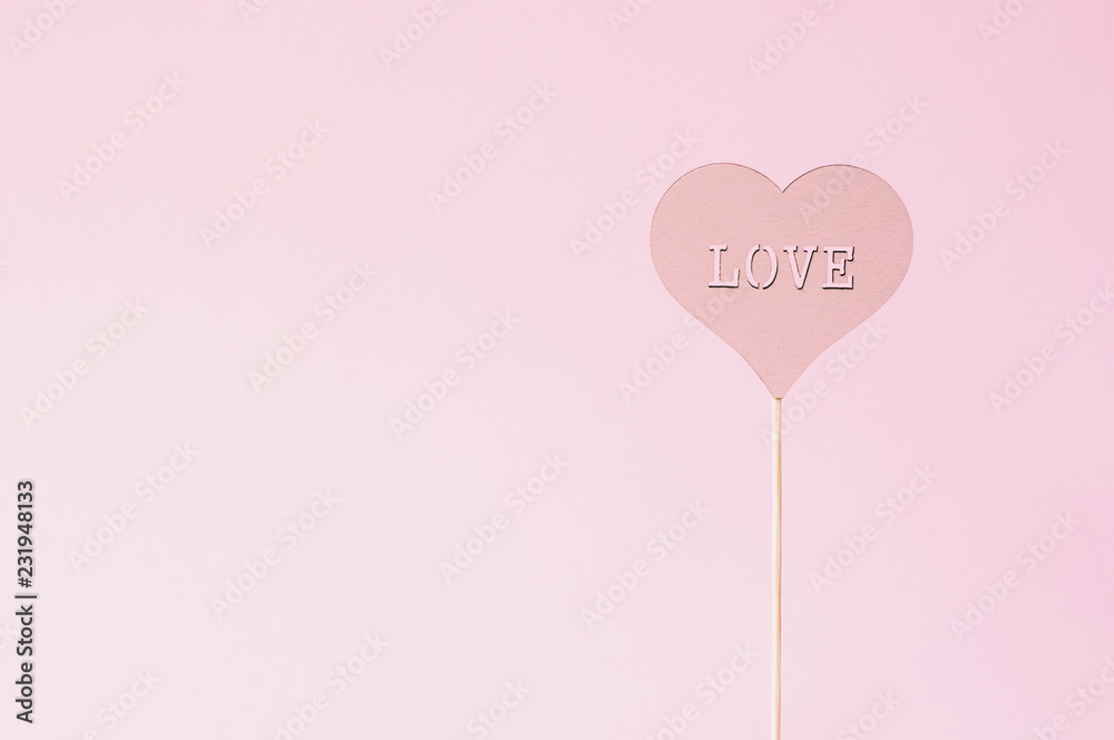 Heart with the inscription love on a wooden stick. Pastel color. Holiday background