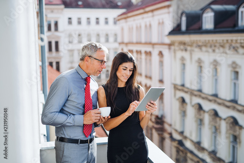 Photography Man and woman business partners with tablet standing on a terrace in city, talking