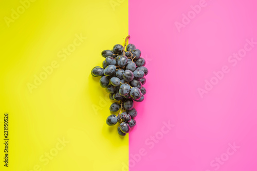 top view of flat lay of bunch of grapes on double color sirface background f photo