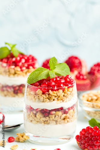 Pomegranate parfait - sweet organic layered dessert with granola flakes, yogurt and ripe fruit seeds.
