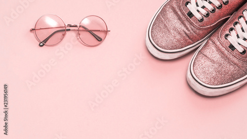 Bright shiny sneakers and glasses on a pastel pink background. Powder color