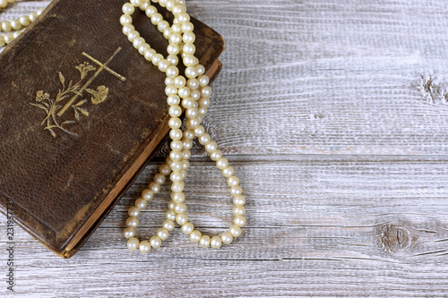 Old holy bible and rosary beads on rustic wooden table