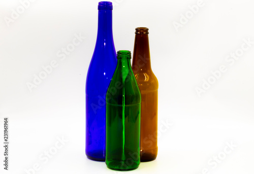 Colored empty glass bottles on white background