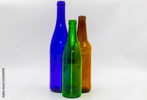 Colored empty glass bottles on white background