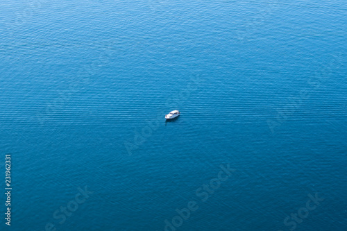 lonely boat in the middle of a calm blue sea
