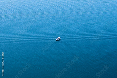 lonely boat in the middle of a calm blue sea