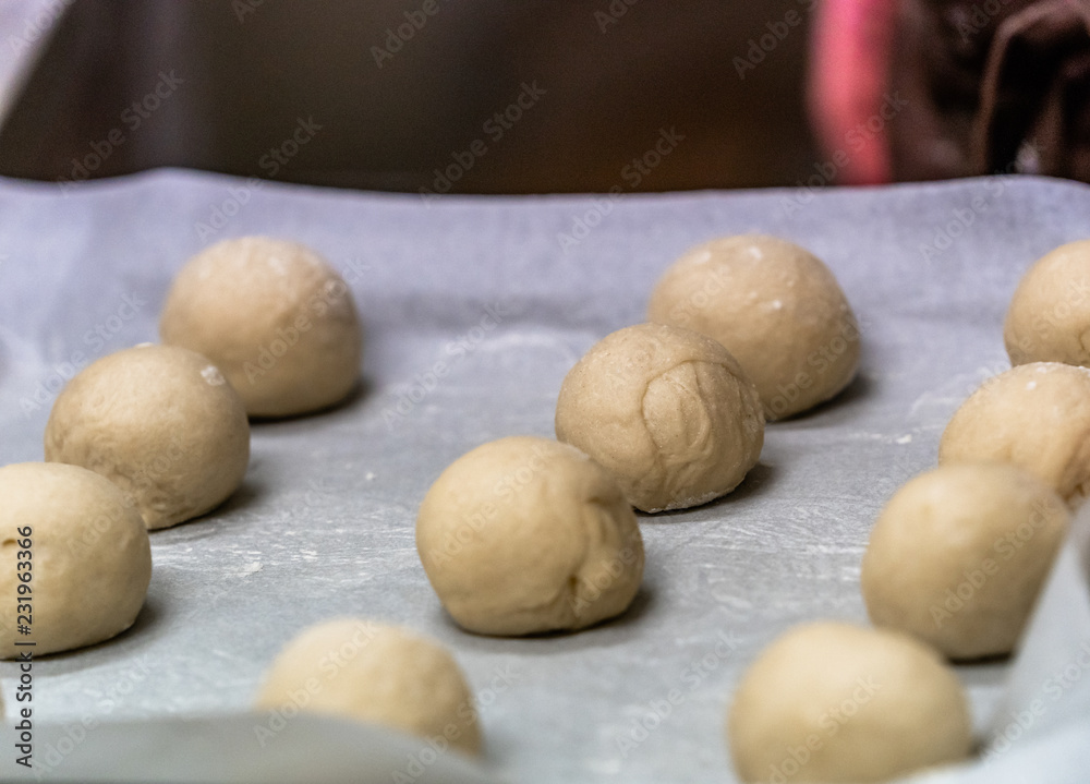 Small Bread Dough Balls Placed on Cooking Paper on Pan - Ready to be Baked Small Bread Dough Balls Placed on Cooking Paper on Pan - Ready to be Baked