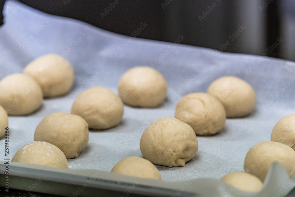 Small Bread Dough Balls Placed on Cooking Paper on Pan - Ready to be Baked Small Bread Dough Balls Placed on Cooking Paper on Pan - Ready to be Baked