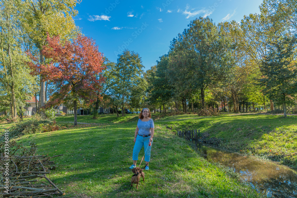 beautiful image of a woman with casual clothes walking with her dachshund on a beautiful autumn day in Voerendaal South Limburg in the Netherlands Holland