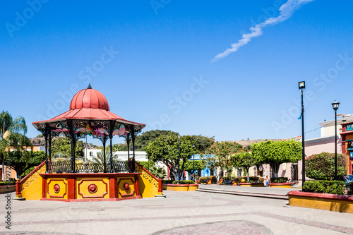 Kiosk with black metal, red dome and painted yellow with red details in the main square of the town of Tequila, wonderful sunny day with a blue sky and few white clouds in Jalisco Mexico photo