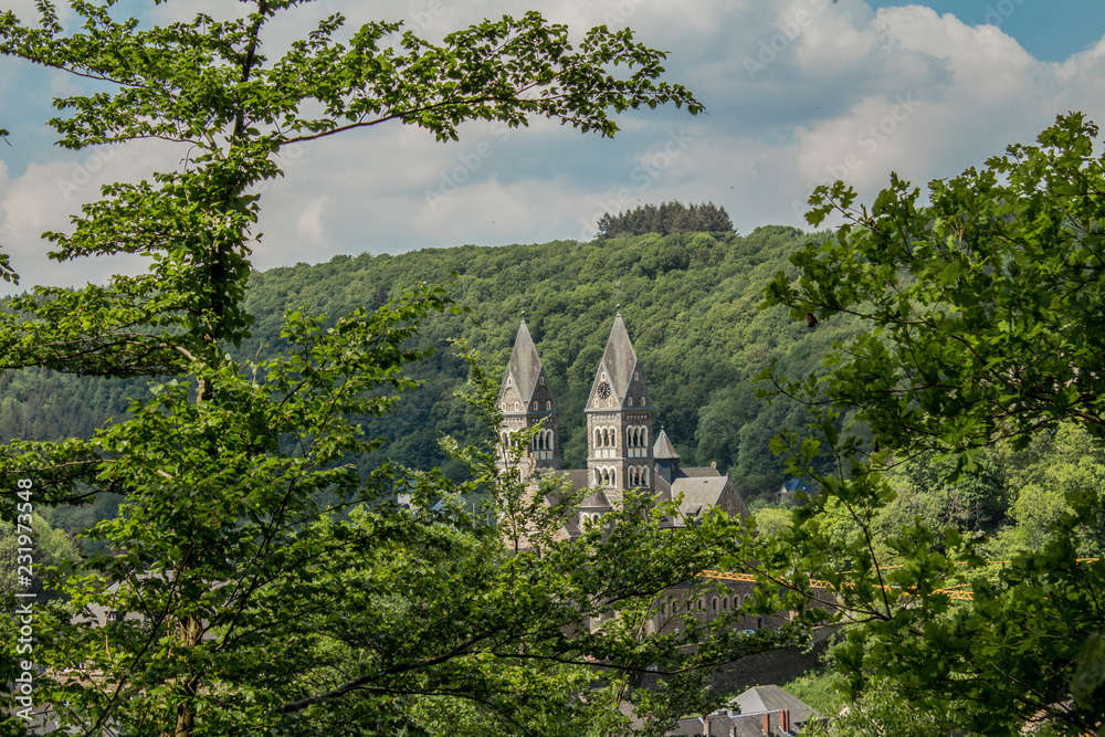 beautiful view of the towers of the Church Saints Cosmas and Damian in Clervaux Luxembourg from the mountain with lots of green vegetation