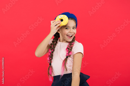 Impossible to resist fresh made donut. Girl hold glazed cute donut in hand red background. Kid playful girl ready to eat donut. Sweets shop and bakery concept. Kids huge fans of baked donuts