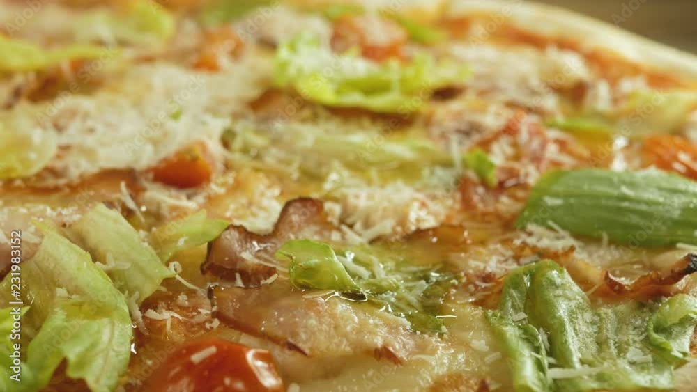 pizza with bacon, cheese, tomatoes, red onions and leaves, rotating on wooden background, close-up, rustic style pizza with bacon, cheese, tomatoes, red onions and leaves, rotating on wooden background, close-up, rustic style
