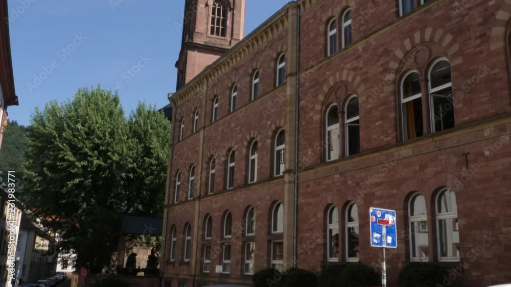 Camera pans right across red brick building. At back corner behind the building is the tower of Jesuit Church (Parish church Holy Ghost and St. Ignatius), and then the camera tilts up along the tower. Camera pans right across red brick building. At back corner behind the building is the tower of Jesuit Church (Parish church Holy Ghost and St. Ignatius), and then the camera tilts up along the tower.
