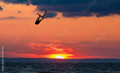 Jumping kitesurfer with a dramatic sunset in the background