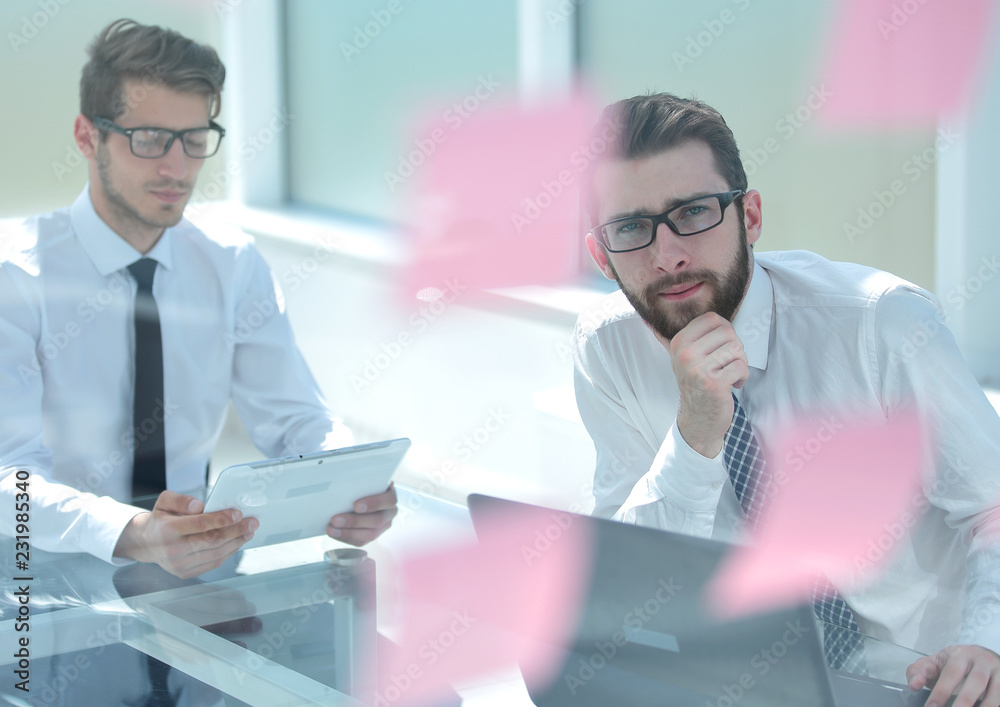 two thoughtful employees sitting at a Desk.