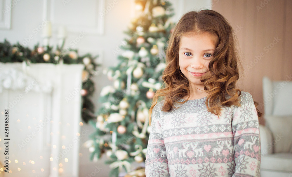 Merry Christmas and Happy New Year. Beautiful, little girl in New Year's environment. A child in a knitted sweater and knitted boots.