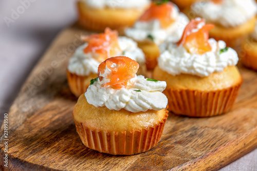 Muffin with salmon with whipped cream and cheese on wooden board, selective focus.