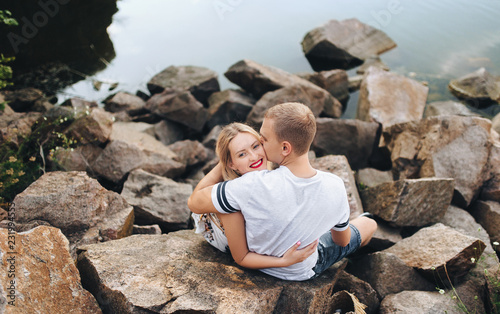 Young boy and girl are hugging on the background of stones and small river. Beautiful love story of newlywed lovers.