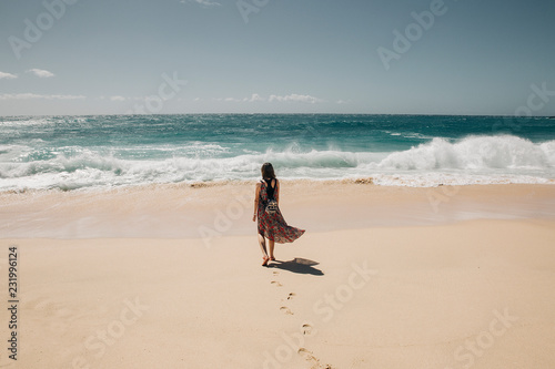 Young woman with long dress walking at Sandy beach in Oahu