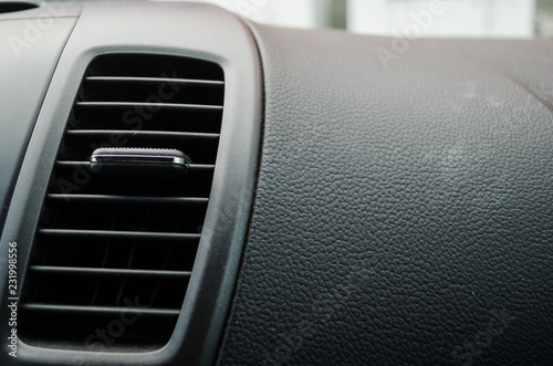 close up to an air conditioner fan inside a modern car, black leather board of a modern car