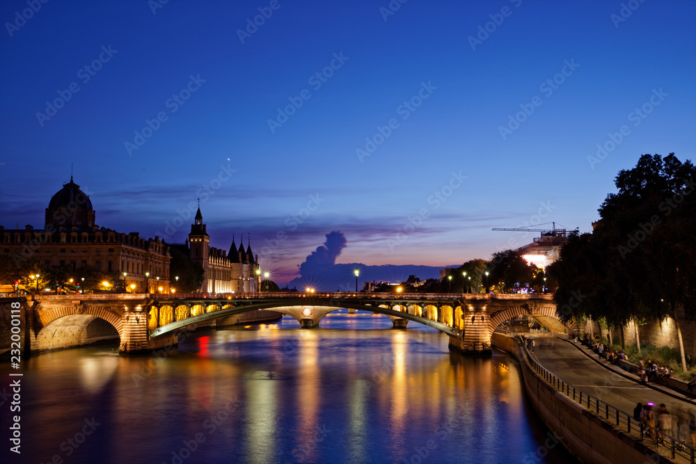 Paris, France - July 5, 2018: Conciergerie  with Paris cityscape and River Seine at dusk, France