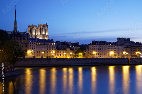 Paris, France - July 5, 2018: Notre Dame Cathedral with Paris cityscape and River Seine at dusk, France