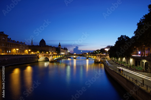 Paris, France - July 5, 2018: Conciergerie with Paris cityscape and River Seine at dusk, France