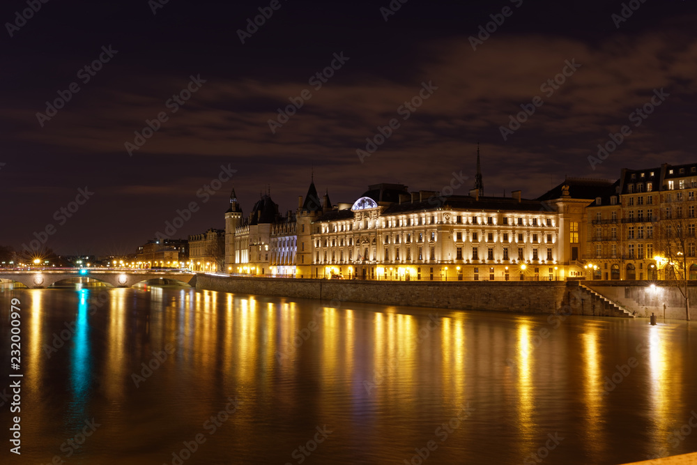 Obraz premium Paris, France - February 18, 2018: View of the Conciergerie on the Ile de la Cite in Paris by night from Pont neuf bridge