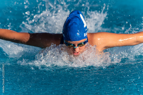 Female swimmer with arms out and pulling water as she speeds toward the finish line during butterfly stroke heat.