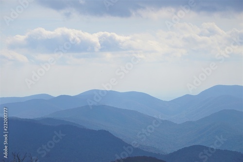 The fantastic view from Brasstown Bald mountain ( the highest mountain in Georgia) on a hazy day, mountains looks silhouette with white fluffy clouds and blue sky, North Georgia in USA.