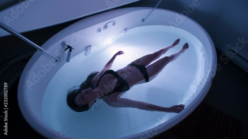 Young Woman in float tank, sensory depravation tank at spa