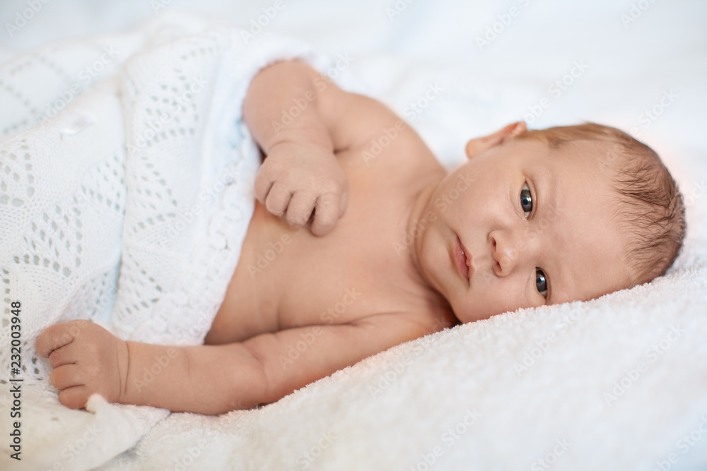 Little newborn baby boy sleeping in white blanket, lying on bed. Little newborn baby boy sleeping in white blanket, lying on bed.