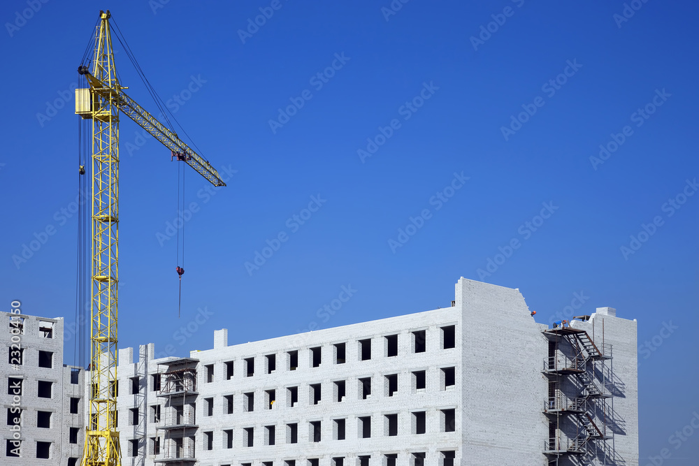 Fototapeta premium Construction crane on the construction of a brick house