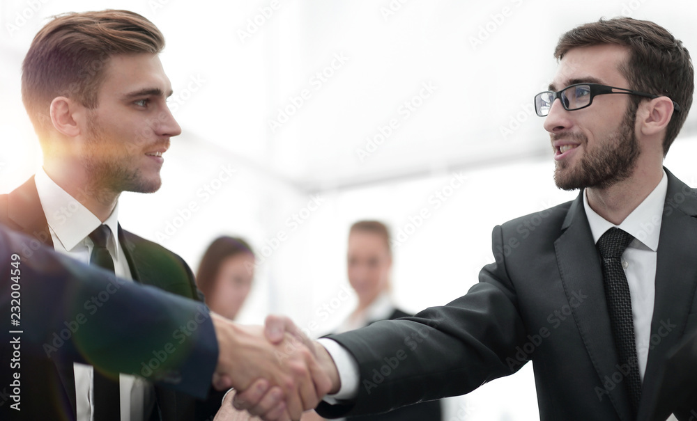 Partners concluding deal and shaking hands in the presence of team members Partners concluding deal and shaking hands in the presence of team members
