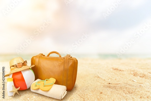 Straw hat, bag, flip flops on a tropical beach