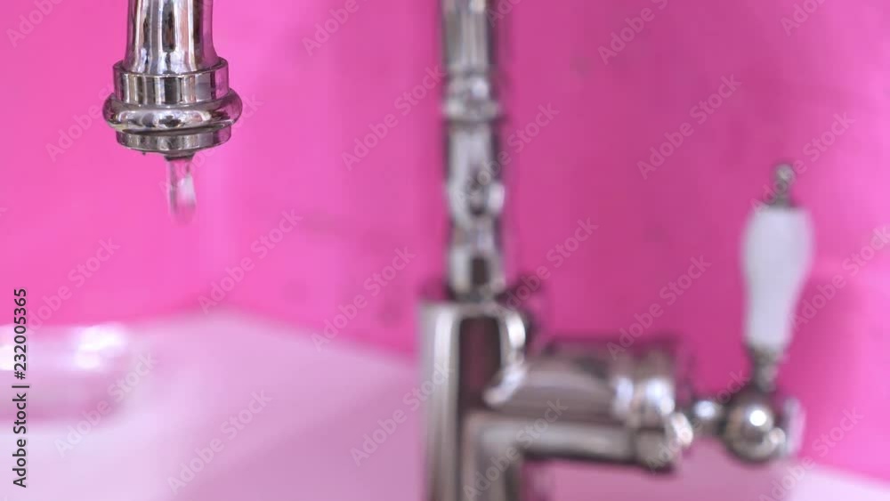Modern faucet with running water at apartment with pink walls Modern faucet with running water at apartment with pink walls