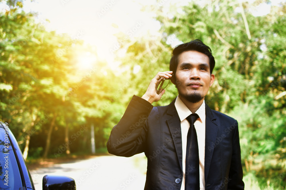 Businessman holding smart phone and standing at car Businessman holding smart phone and standing at car