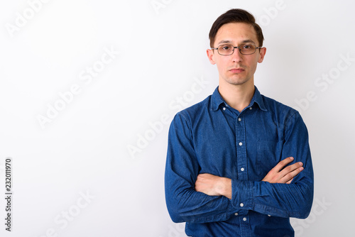 Studio shot of young handsome man wearing eyeglasses with arms c