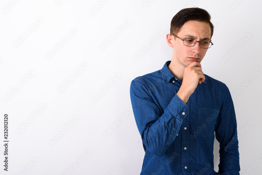 Studio shot of stressed young man thinking and looking down whil Studio shot of stressed young man thinking and looking down whil