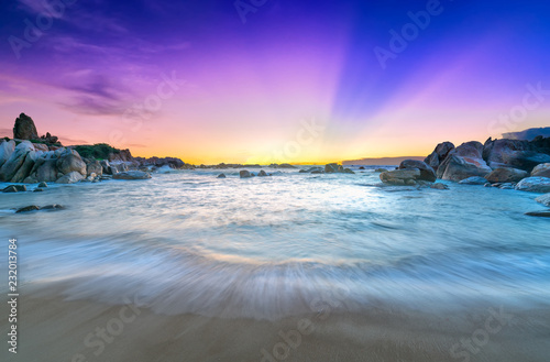 Beautiful sunrise on the beach as the sun rays in the sky purple and below the waves lapping at the shore of the soft great to welcome the new day