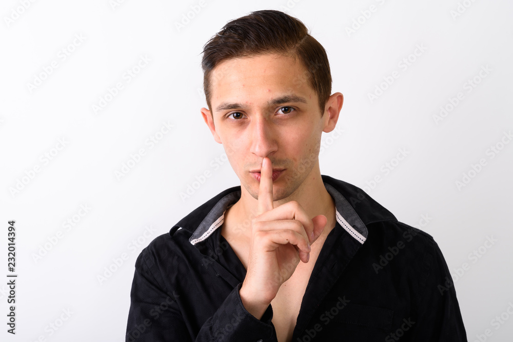 Close up of young handsome man with finger on lips and shirt ope Close up of young handsome man with finger on lips and shirt ope