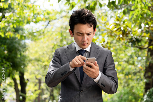 外で携帯電話を確認するビジネスマン