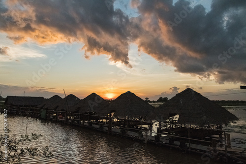 magical sunset with reflections in the lake with traditional straw huts